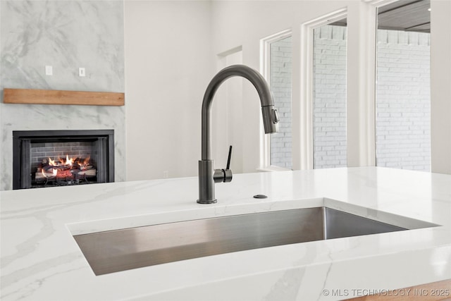room details with a sink, a high end fireplace, and light stone countertops