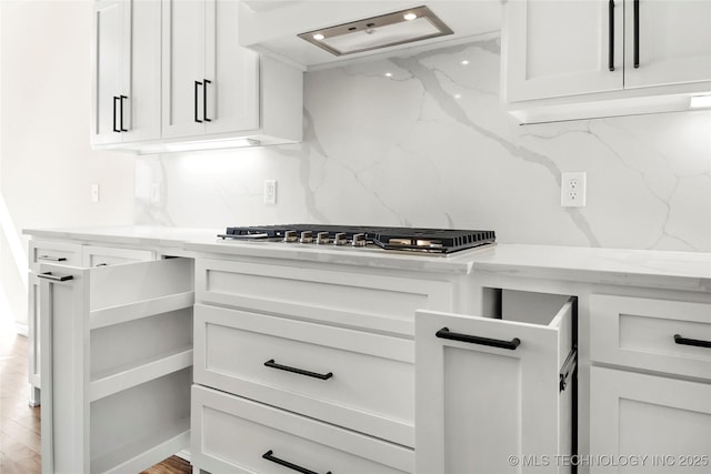 kitchen with stainless steel gas cooktop, ventilation hood, backsplash, and white cabinets