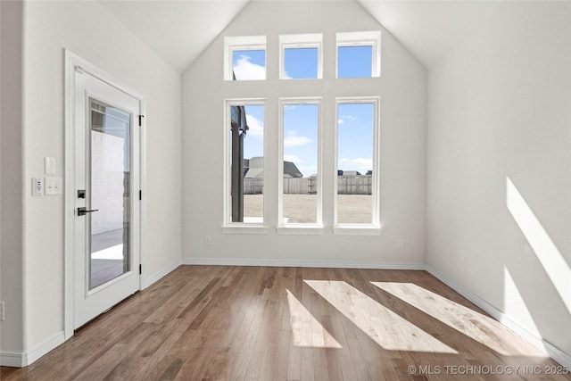 interior space with lofted ceiling, baseboards, and wood finished floors