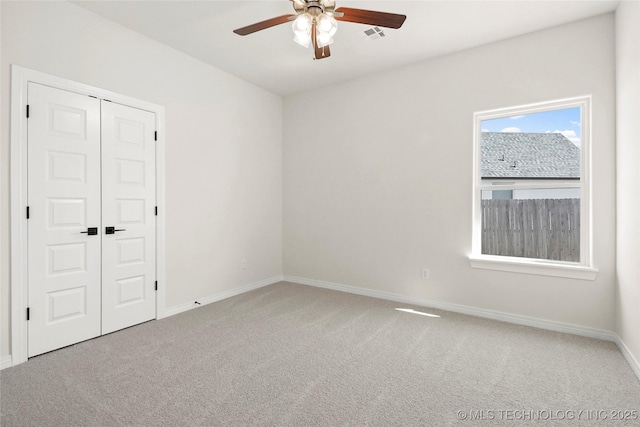 carpeted spare room with visible vents, ceiling fan, and baseboards