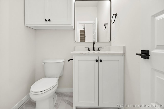 half bathroom with vanity, marble finish floor, baseboards, and toilet