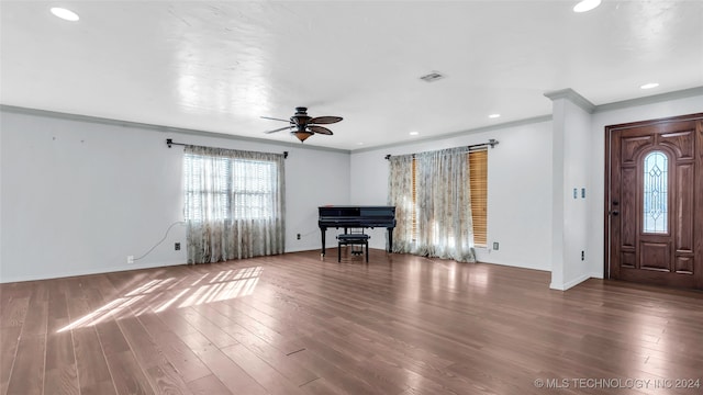 unfurnished living room featuring ceiling fan, dark hardwood / wood-style flooring, and ornamental molding