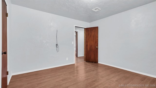 empty room with a textured ceiling and hardwood / wood-style flooring