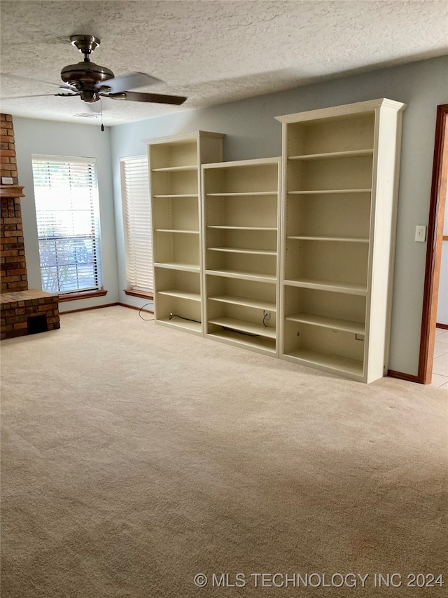 unfurnished living room featuring a textured ceiling, light colored carpet, and ceiling fan