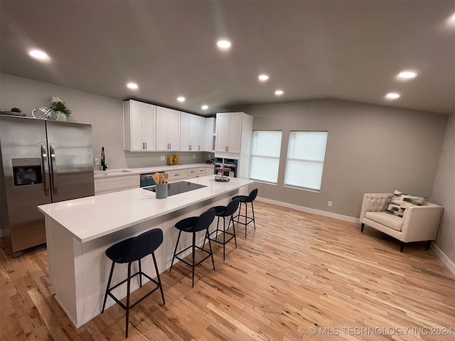 kitchen with white cabinetry, sink, light hardwood / wood-style flooring, a breakfast bar area, and appliances with stainless steel finishes