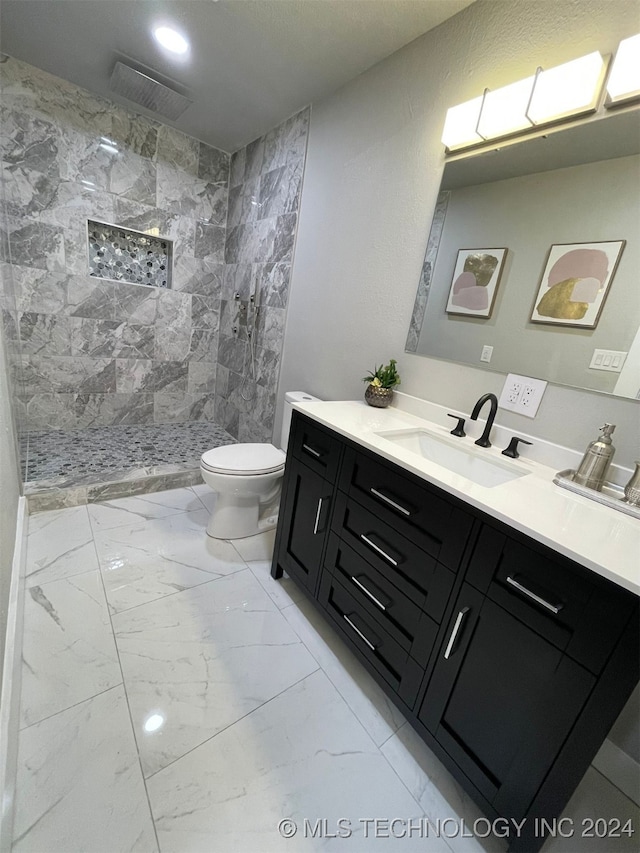 bathroom with a tile shower, vanity, and toilet