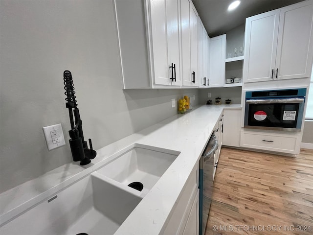 kitchen featuring white cabinets, light wood-type flooring, stainless steel appliances, and sink