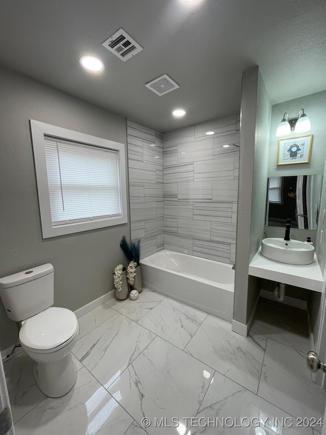 full bathroom with tiled shower / bath combo, toilet, and sink