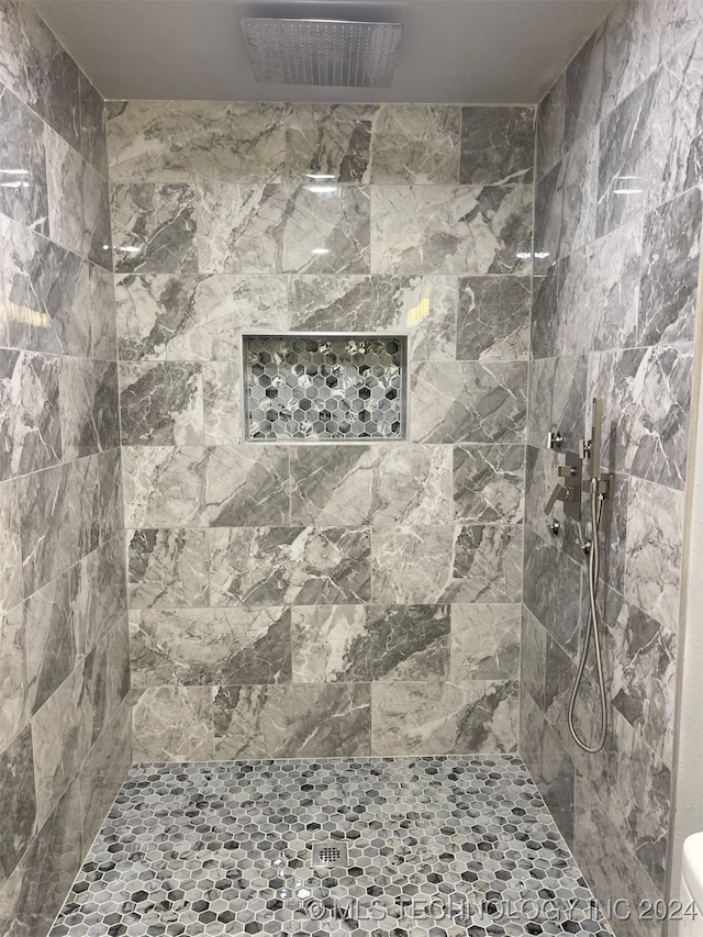 bathroom with a tile shower and toilet