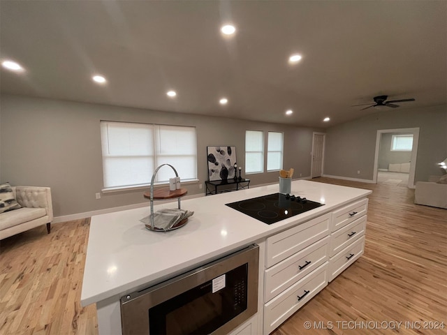 kitchen featuring white cabinetry, stainless steel microwave, light hardwood / wood-style flooring, black electric stovetop, and a kitchen island