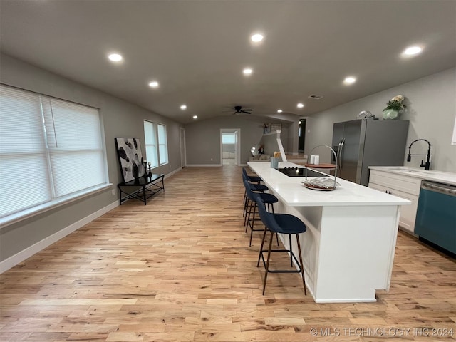 kitchen featuring lofted ceiling, stainless steel appliances, a kitchen island with sink, and light hardwood / wood-style flooring