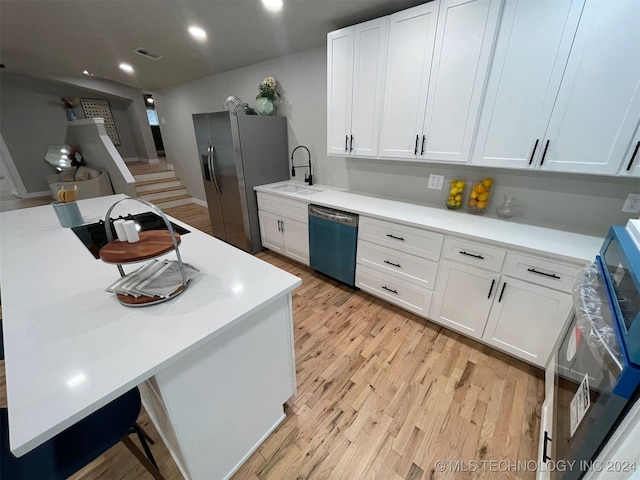 kitchen with stainless steel appliances, white cabinetry, light hardwood / wood-style floors, and sink