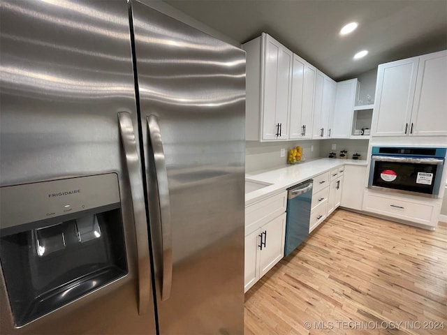 kitchen with white cabinets, light wood-type flooring, and stainless steel appliances