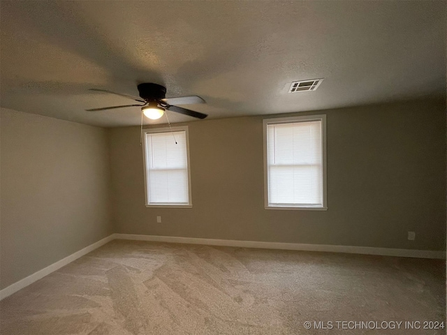 empty room with ceiling fan, carpet floors, and a textured ceiling