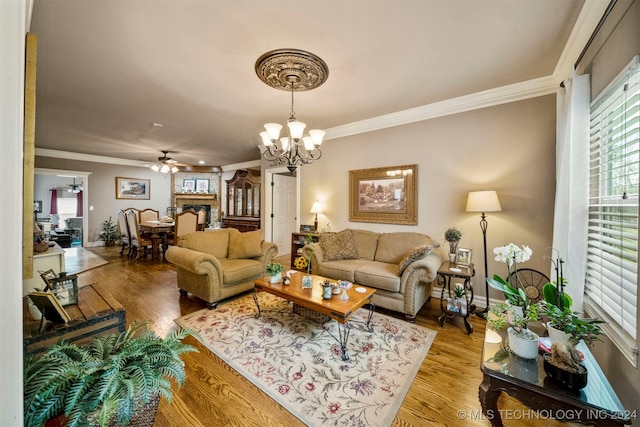 living room with hardwood / wood-style flooring, ornamental molding, a fireplace, and ceiling fan with notable chandelier