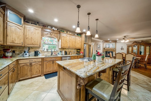 kitchen featuring appliances with stainless steel finishes, decorative light fixtures, sink, decorative backsplash, and a center island