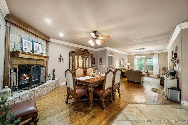 dining area featuring crown molding, ceiling fan with notable chandelier, a fireplace, and light hardwood / wood-style floors