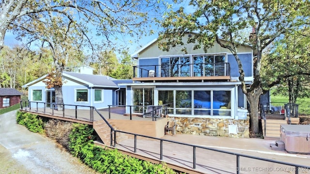 back of house featuring a wooden deck, a sunroom, and a hot tub