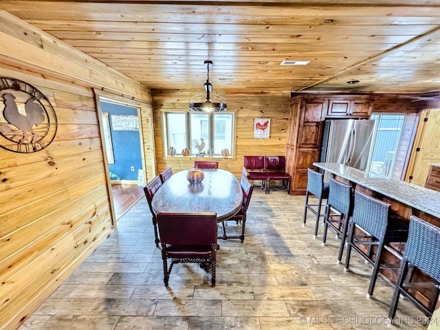 dining room featuring wooden ceiling and wooden walls