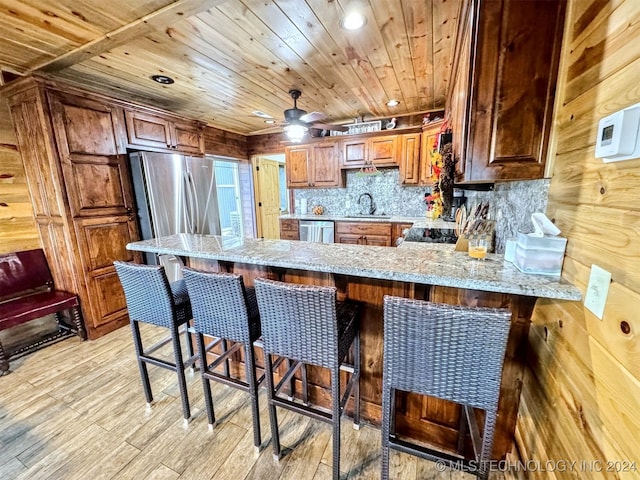 kitchen featuring stainless steel dishwasher, a breakfast bar, kitchen peninsula, and light hardwood / wood-style flooring