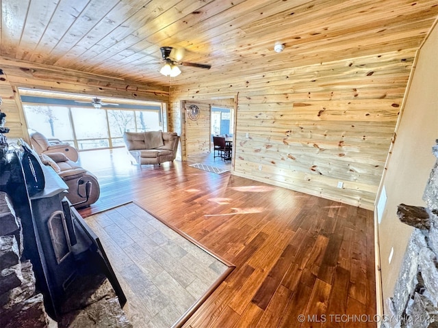 unfurnished living room with hardwood / wood-style flooring, ceiling fan, wood ceiling, and wooden walls