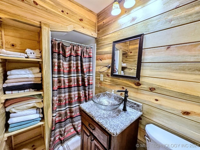 bathroom with vanity, toilet, and wooden walls