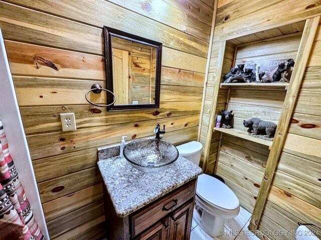 bathroom featuring wooden walls, tile patterned flooring, vanity, and toilet