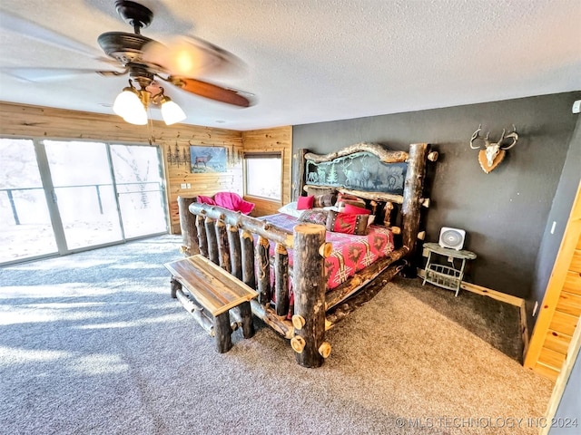 carpeted bedroom featuring multiple windows, ceiling fan, wooden walls, and a textured ceiling