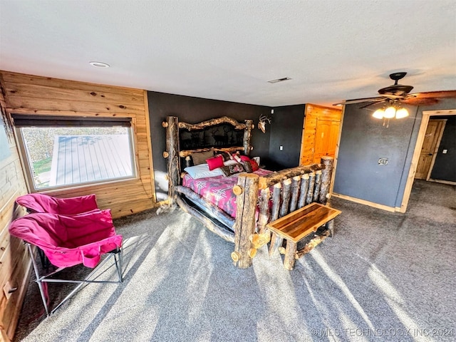 bedroom with ceiling fan, carpet floors, a textured ceiling, and wooden walls