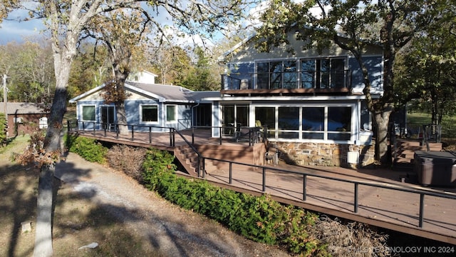 rear view of property featuring a sunroom and a deck