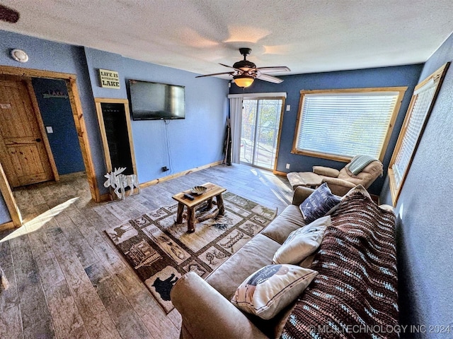 living room with wood-type flooring, a textured ceiling, and ceiling fan