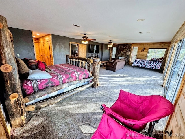 carpeted bedroom with ceiling fan and wooden walls