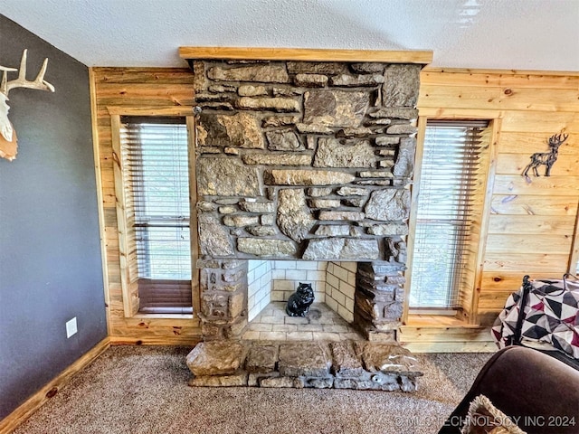 living room featuring wooden walls, a fireplace, and a textured ceiling