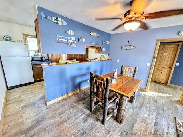 dining space with ceiling fan, a textured ceiling, and light wood-type flooring