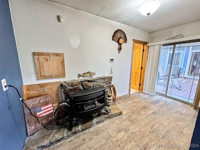 living room with a wood stove, a textured ceiling, and light wood-type flooring