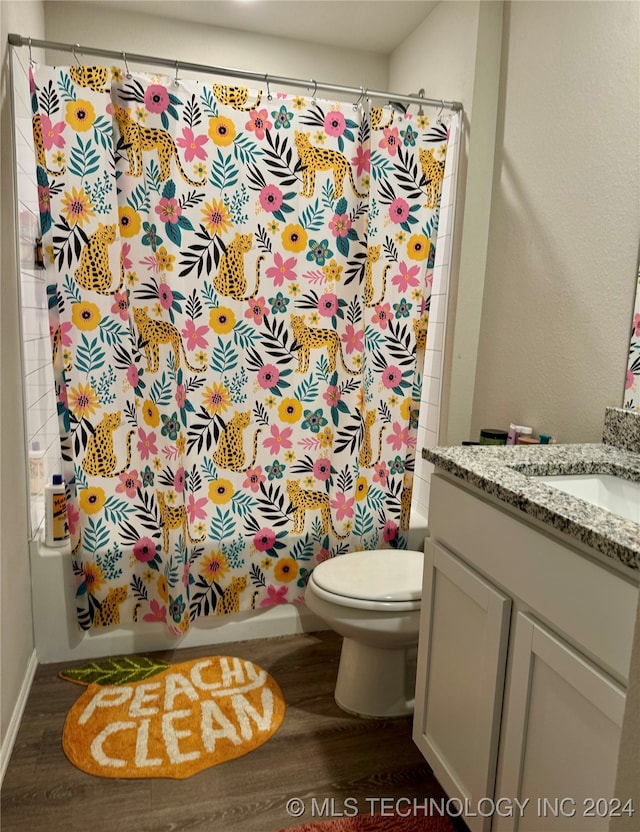 full bathroom featuring hardwood / wood-style floors, vanity, toilet, and shower / tub combo with curtain