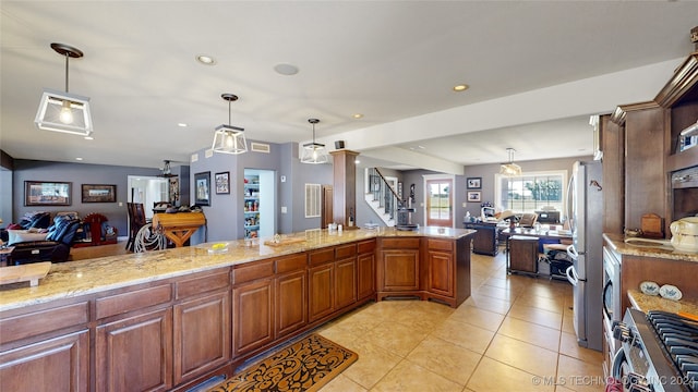 kitchen featuring light stone countertops, appliances with stainless steel finishes, decorative light fixtures, and light tile patterned floors