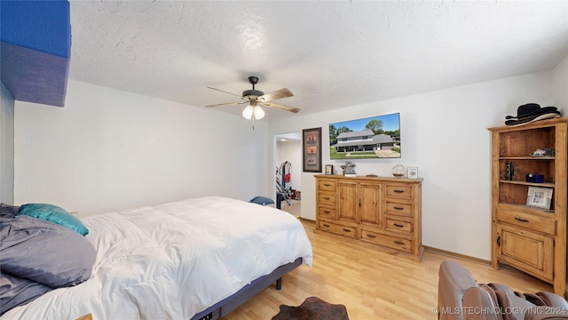 bedroom with a textured ceiling, light hardwood / wood-style floors, and ceiling fan