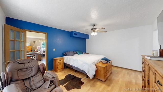 bedroom with ceiling fan, a textured ceiling, and light hardwood / wood-style flooring