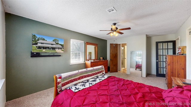 carpeted bedroom with a textured ceiling, ceiling fan, and ensuite bathroom