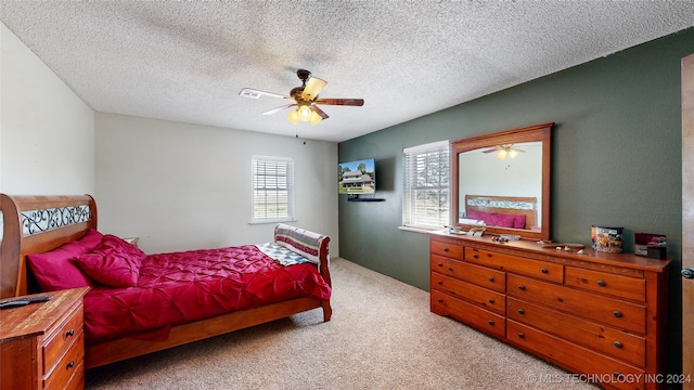 carpeted bedroom featuring ceiling fan and a textured ceiling