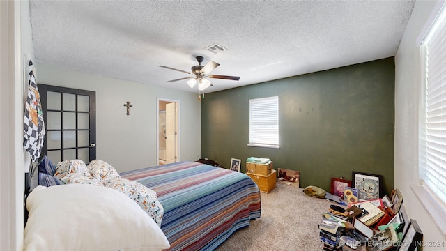 carpeted bedroom featuring a textured ceiling, ensuite bathroom, and ceiling fan