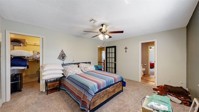 carpeted bedroom with ceiling fan, ensuite bathroom, and a textured ceiling