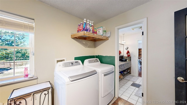 washroom with a wealth of natural light, light tile patterned floors, a textured ceiling, and independent washer and dryer