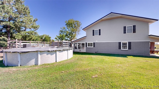 rear view of property with a yard and a covered pool