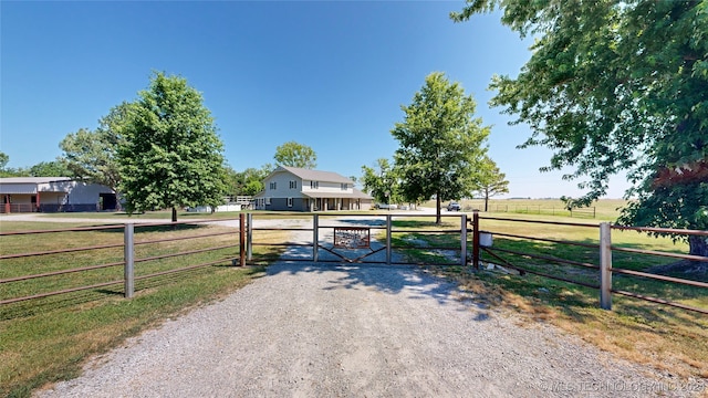 view of gate with a rural view and a lawn