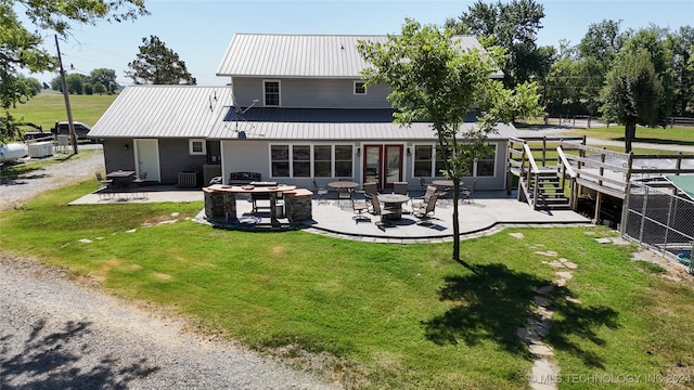 back of property with a patio, an outdoor fire pit, cooling unit, and a lawn