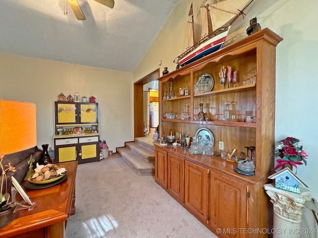 bar featuring a textured ceiling, ceiling fan, light carpet, and vaulted ceiling