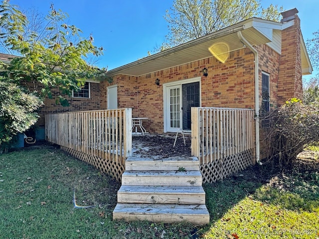 view of exterior entry featuring a yard and a wooden deck