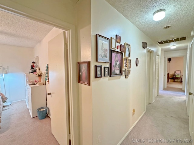 hall featuring light carpet and a textured ceiling